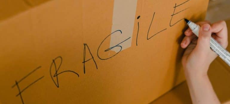 crop-person-packing-box-with-fragile-items